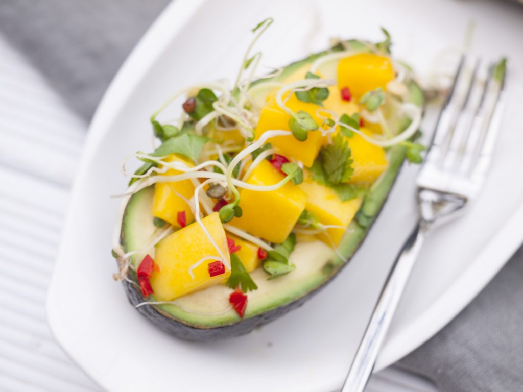 Mango geschnitten in Avocadohälfte