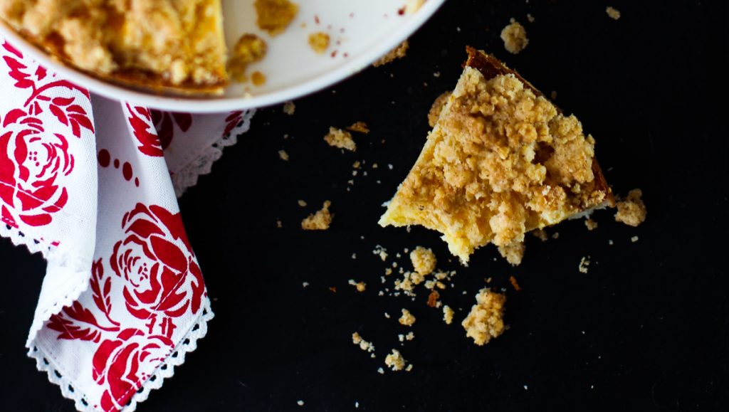 angebissenes Stück Käsekuchen mit Zitronenstreuseln von oben