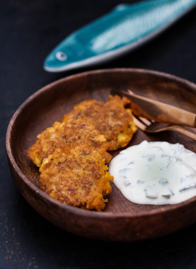 Thunfisch Bratlinge mit Joghurtdip auf einem runden Holzteller Nahaufnahme