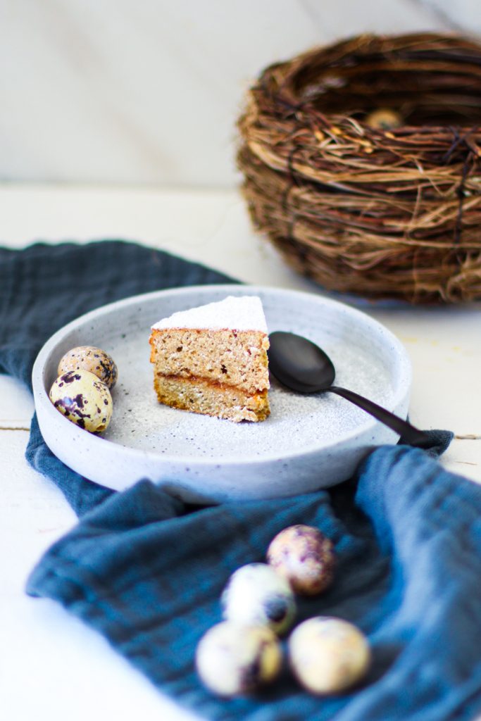 Low Carb Espresso-Kuchen ohne Mehl auf einem weißen Natursteinteller, daneben Wachteleier