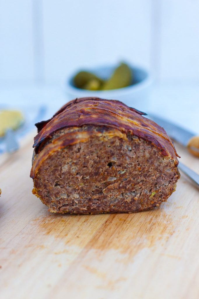 Omas Hackbraten mit Bacon obendrauf, aufgeschnitten auf einem Brett. Nahaufnahme.