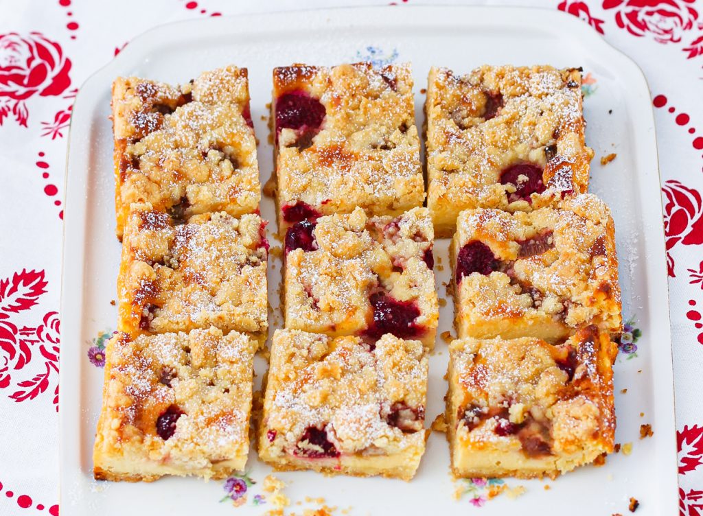 Rhabarber-Himbeer-Käsekuchen, in Stücke geschnitten auf einer alten geblümten Tortenplatte 