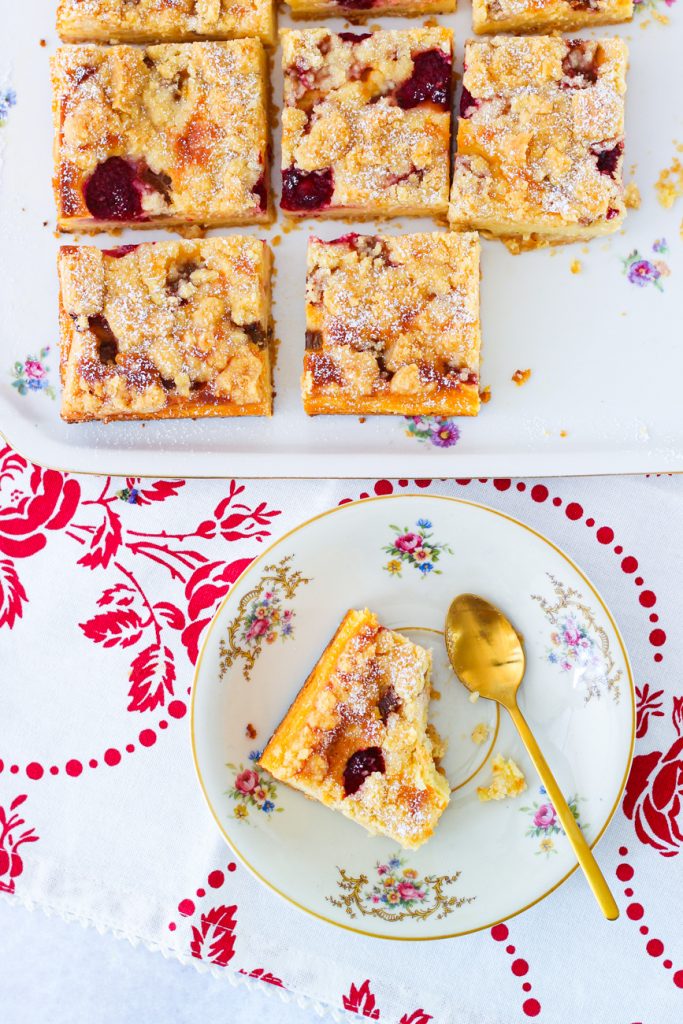 Rhabarber-Himbeer-Käsekuchen, ein Stück auf einem alten Teller mit Blümchen, der Rest daneben.