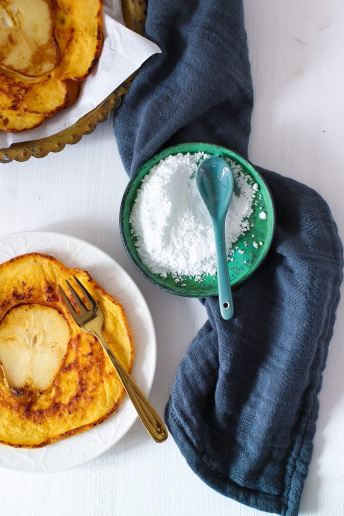 Pfannkuchen mit Birne 
gebraten, auf einem weißen Teller mit goldener Gabel 