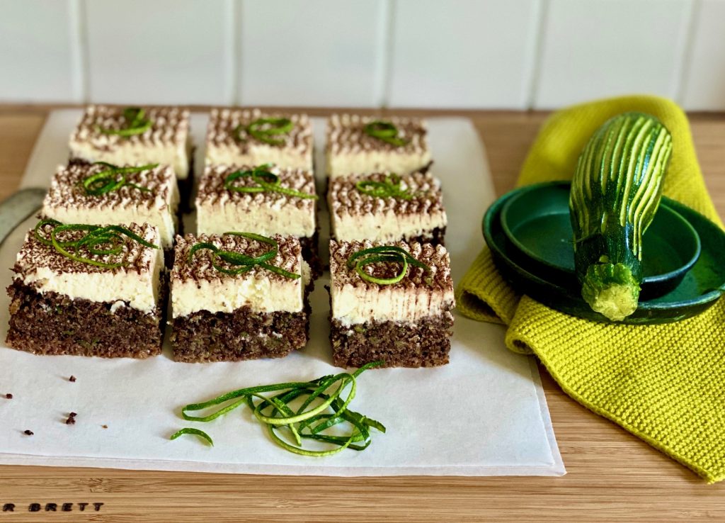 Zucchinikuchen mit Schokolade, Mohn und Rapsöl, aufgeschnitten, daneben eine Zucchini