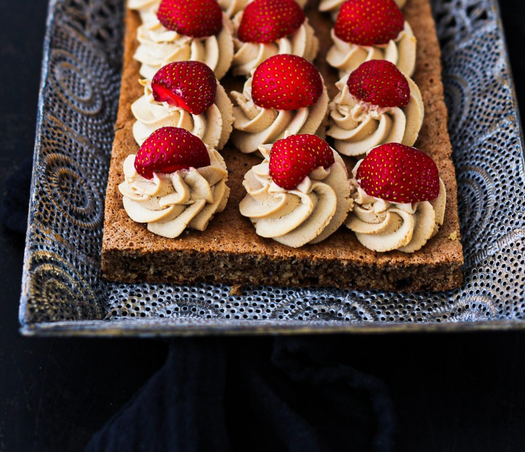 Dunkler Biskuit mit Creme und Erdbeeren auf einem orientalischen silbernen Tablett 