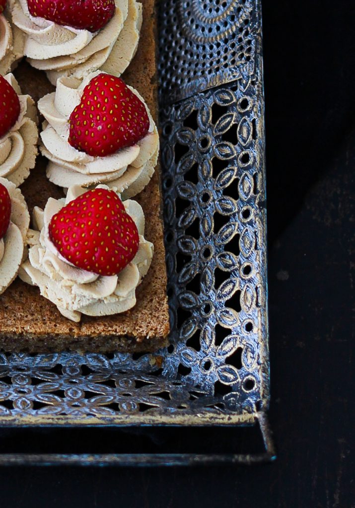 Dunkler Biskuit mit Creme und Erdbeeren auf einem orientalischen silbernen Tablett, Nahaufnahme von oben 