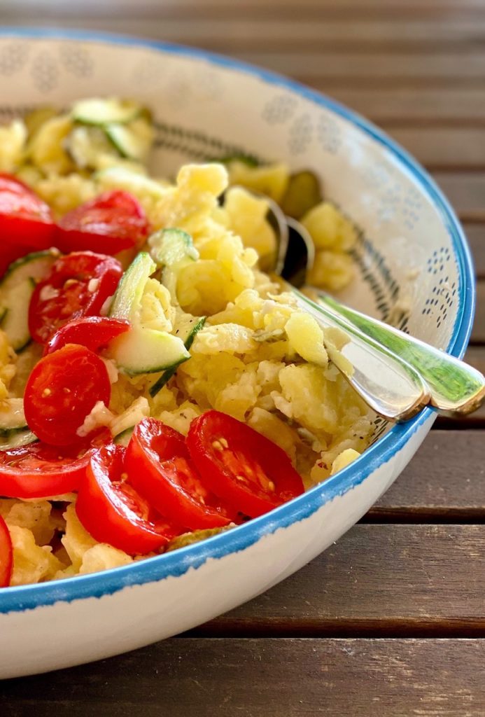 Kartoffelsalat light mit Tomaten und Gurken fertig angemacht in einer bunten großen Schale 