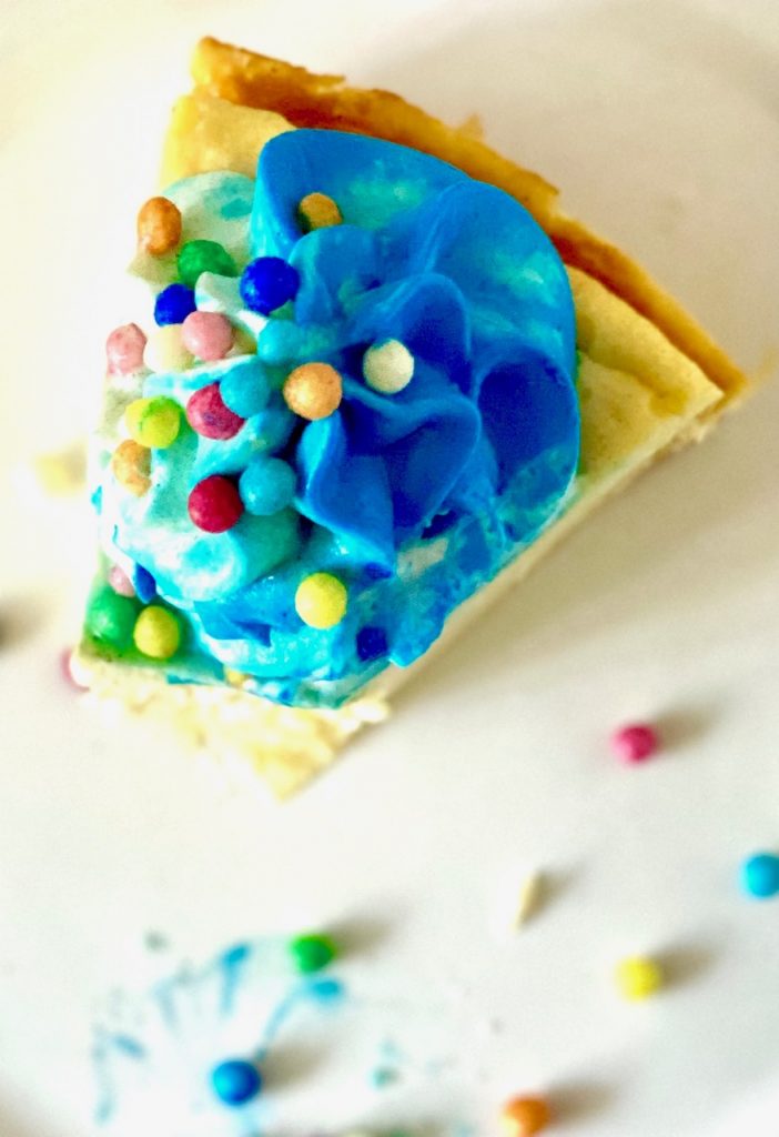 Cheesecake mit blauem Tapping und Zuckerperlen von oben fotografiert. ein Stück angegessen 
