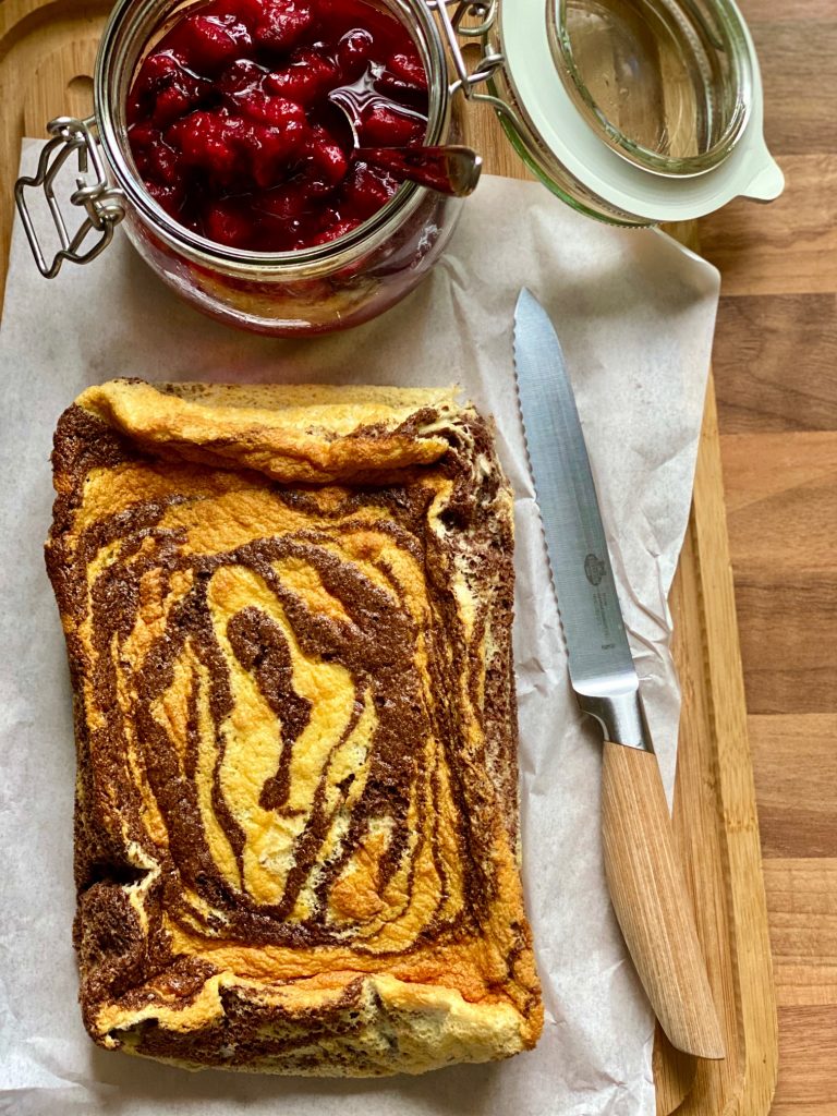 Einfacher Marmor-Joghurtkuchen ohne Mehl und Zucker. Von oben fotografiert, daneben Zwetschgenkompott in einem Glas