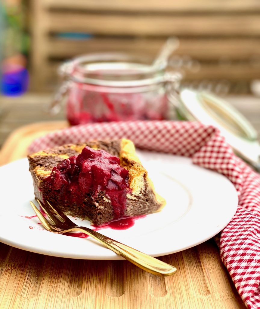 Einfacher Marmor-Joghurtkuchen ohne Mehl und Zucker, ein Stück auf einem weißen Teller mit Kompott, ein Bissen ist schon weg 