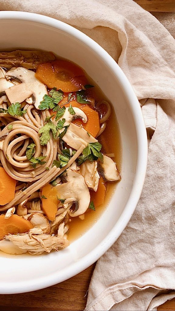Schnelle Misosuppe mit Sobanudeln, Karotten und Champignons in einem weißen Teller von oben fotografiert