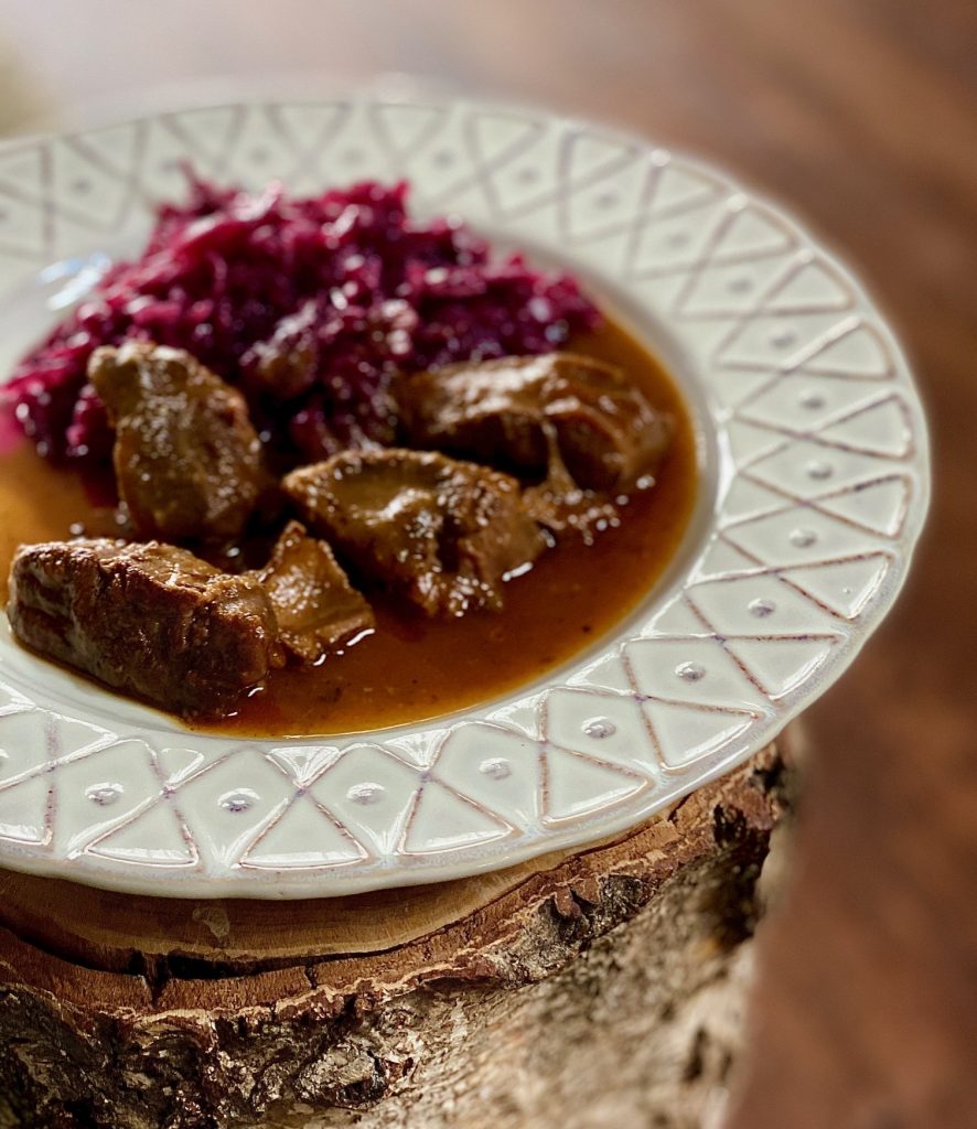 Gulasch aus der Rinderwade mit Rotkohl auf einem Teller 