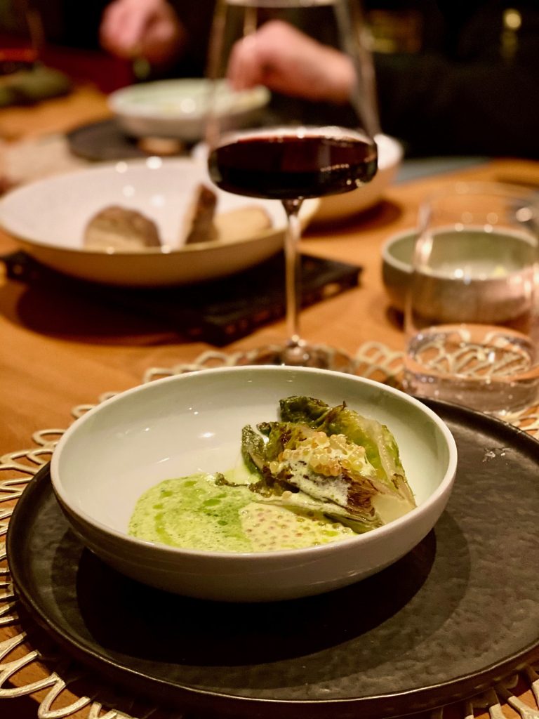 Veles Restaurant Nürnberg kurzgebratenes Salatherz mit einer Vinaigrette aus Saiblings-Rogen, Joghurt und Dill mit Rotwein im Hintergrund 