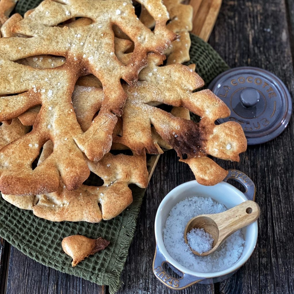 Französische Fougasse - die Provence in einem Brot - auf einem grünen groben Tuch mit Salzbehälter 