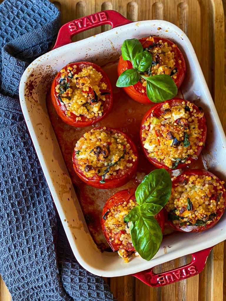 Gefüllte Tomaten (vegetarisch), gebacken und mit Basilikum dekoriert. Foto von oben im roten Bräter.