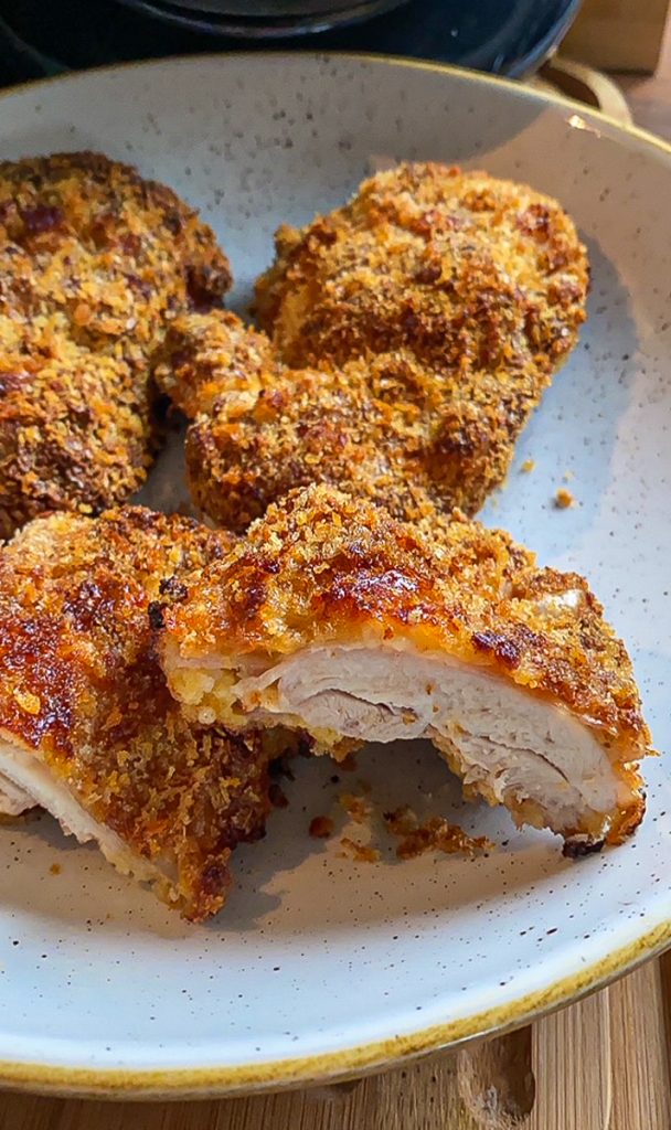 Knusprige Hähnchenschnitzel in Panko. Ein Schnitzel angeschnitten.