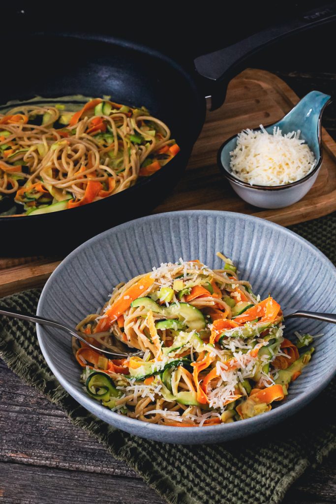 Gemüse-Tagliatelle in schlanker Rahmsoße auf einem Teller mit Besteck 