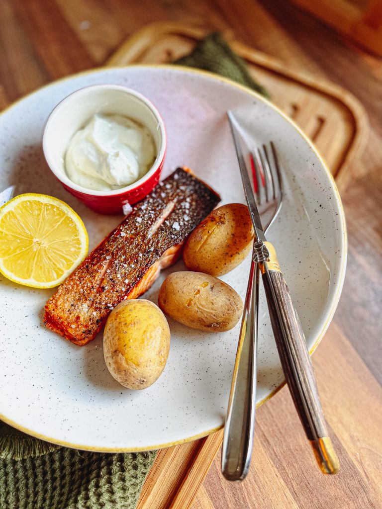 Knuspriges Lachsfilet mit Pellkartoffeln  auf einem Teller mit Besteck