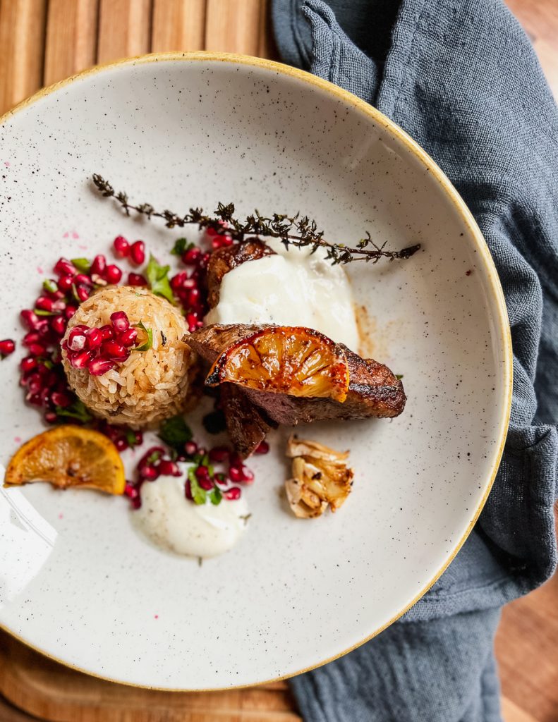 Schlankes Lammfilet mit orientalischem Bratreis & Petersilien-Granatapfel-Salat - auf einem Teller von oben 