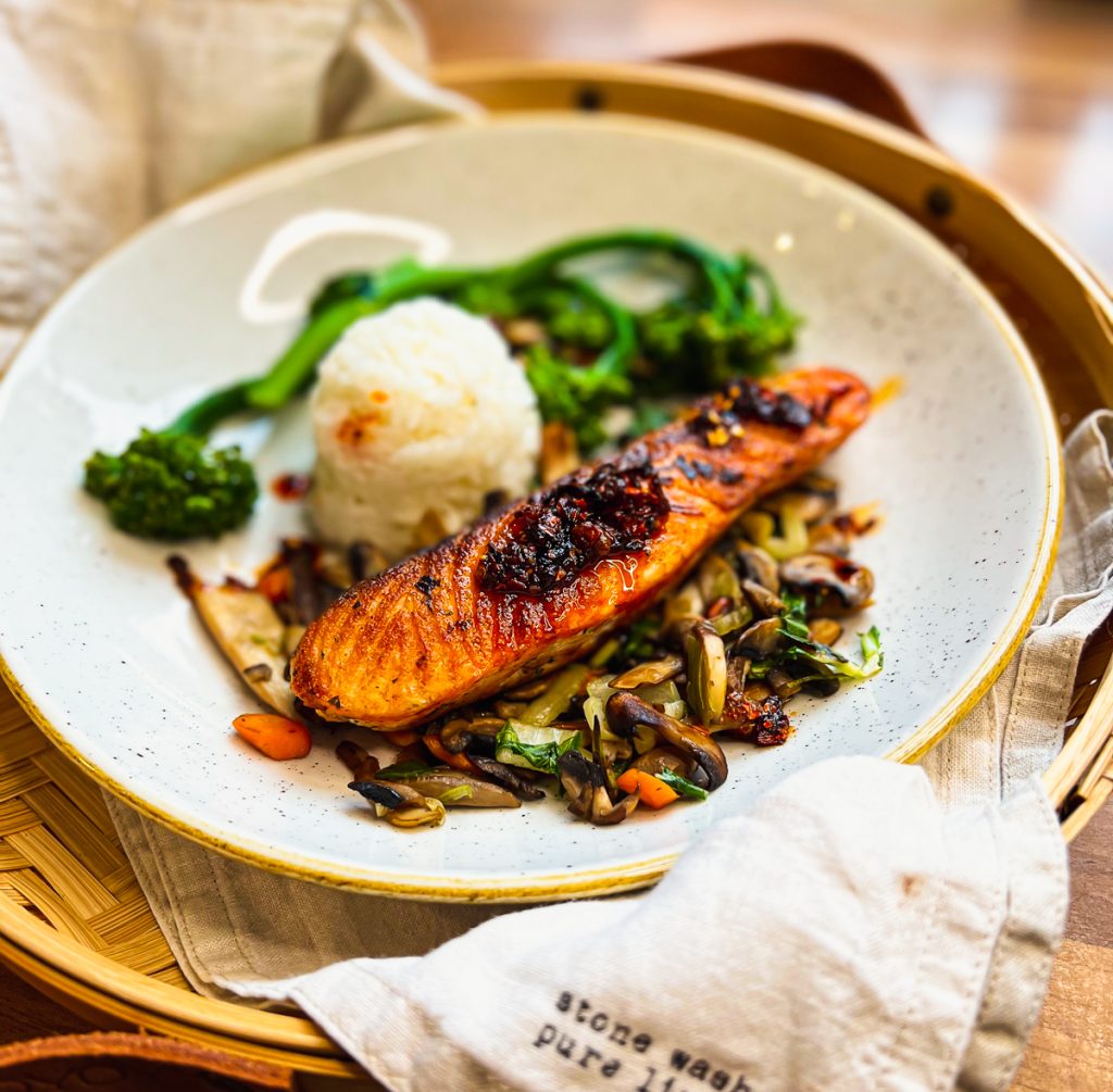 Knuspriger Lachs mit Crispy Chili auf einem weißen Teller