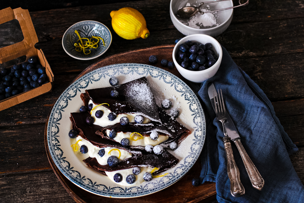 Schoko Crêpes mit Blaubeeren. Mit einer Schachtel Blaubeeren daneben