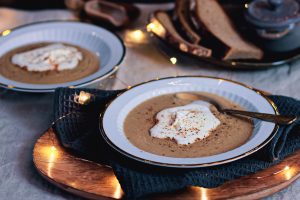 Cremige Maronensuppe mit Sahnehäubchen in Tellern mit Goldrand
