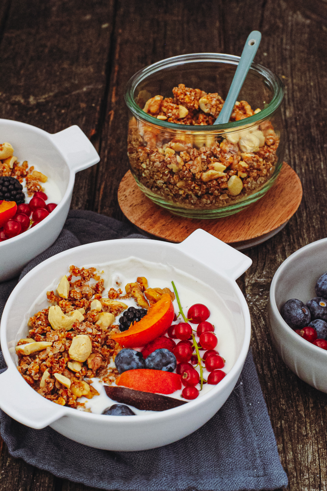 Knuspriges Walnuss-Cashew-Granola mit „versteckten“ Aprikosen in einer weißen Schale mit bunten Beeren