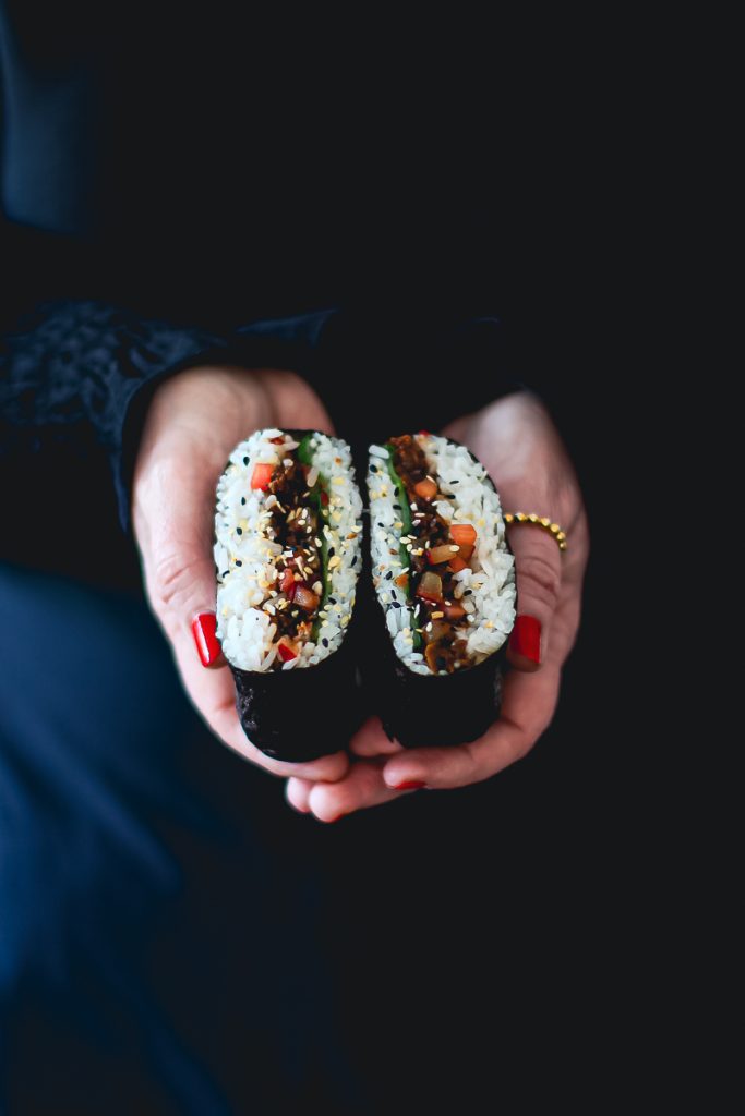 Veganes Sushi Sandwich mit Pflaumen in der Hand