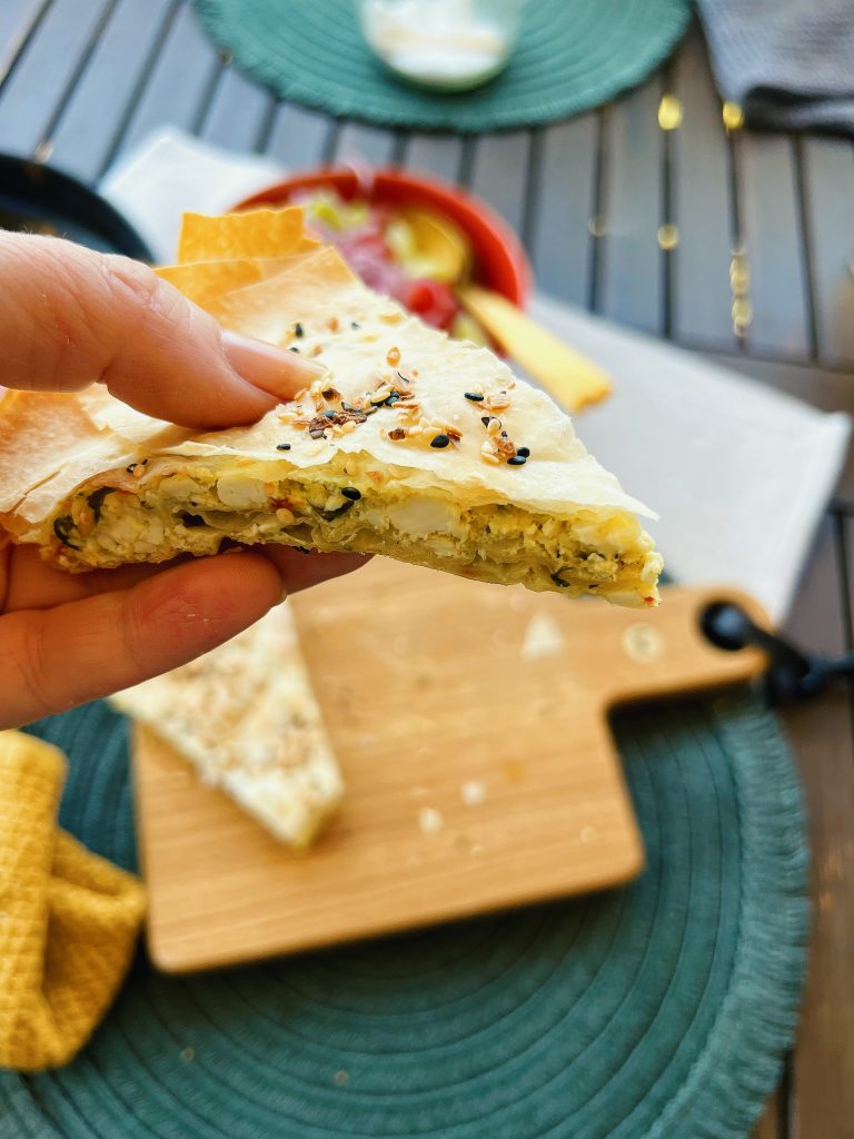 Börek mit Schafskäse, ein Stück in der Hand