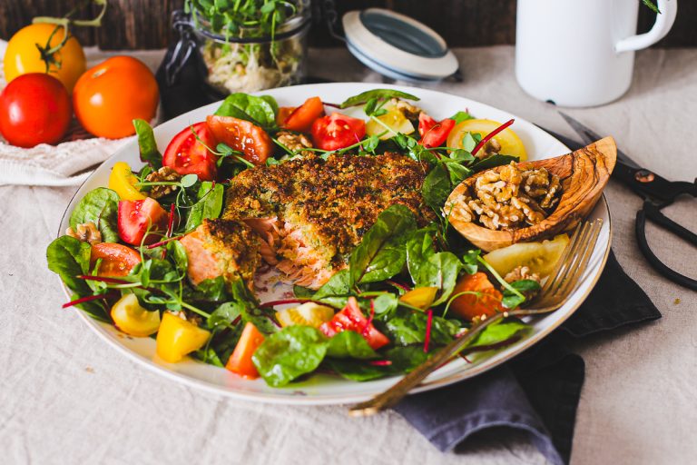 Schnelles Lachsfilet mit köstlicher Walnusskruste auf einer Platte mit Salat angerichtet