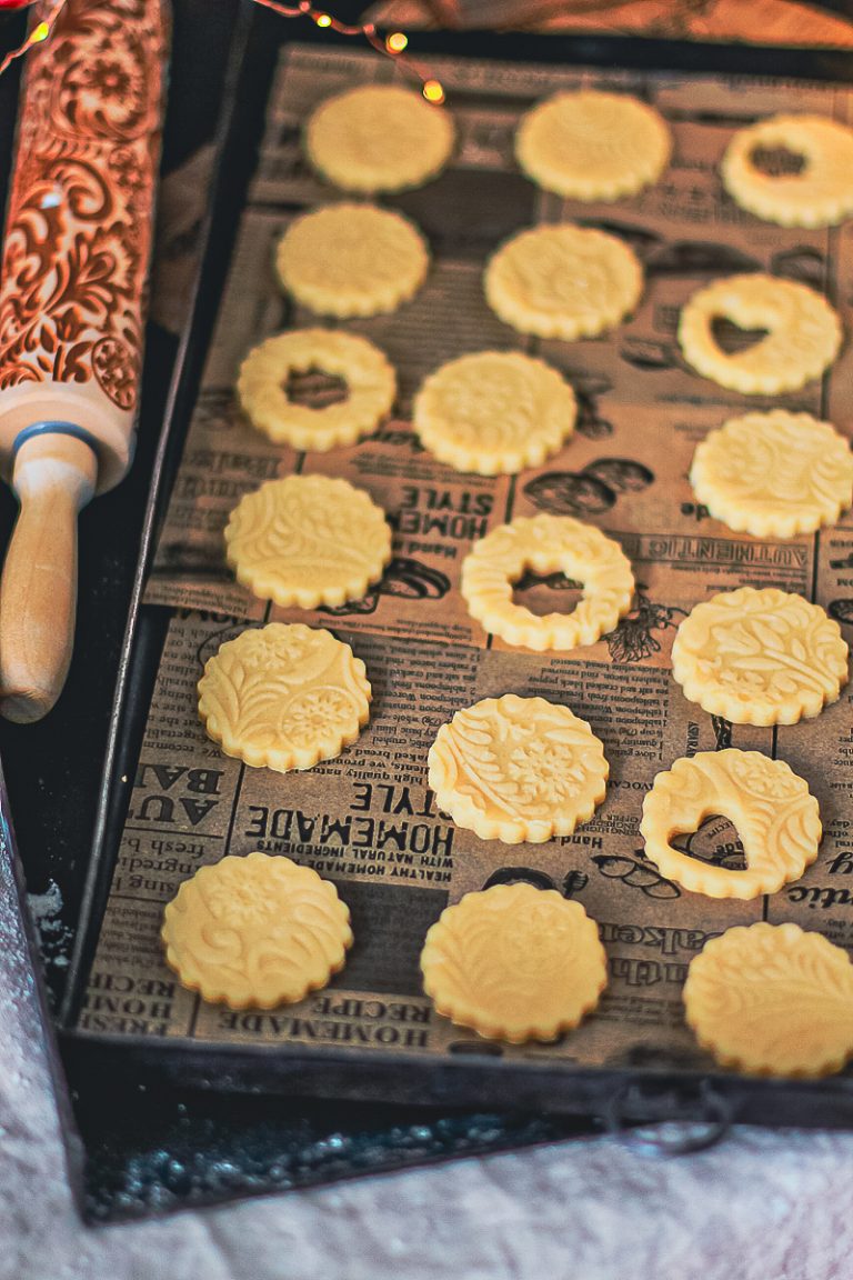 Ausgestochene Butterplätzchen mit Musterteigrolle daneben